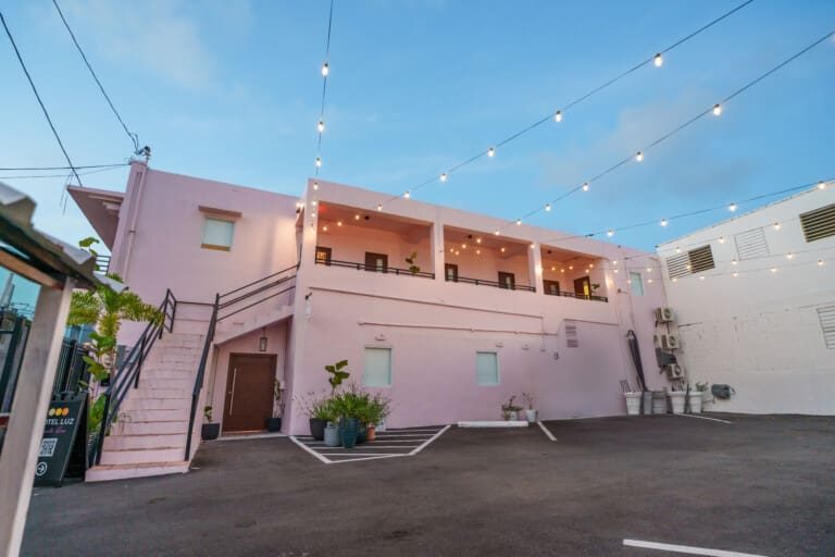The pink facade of Hotel Luz lit with string lights, Santurce