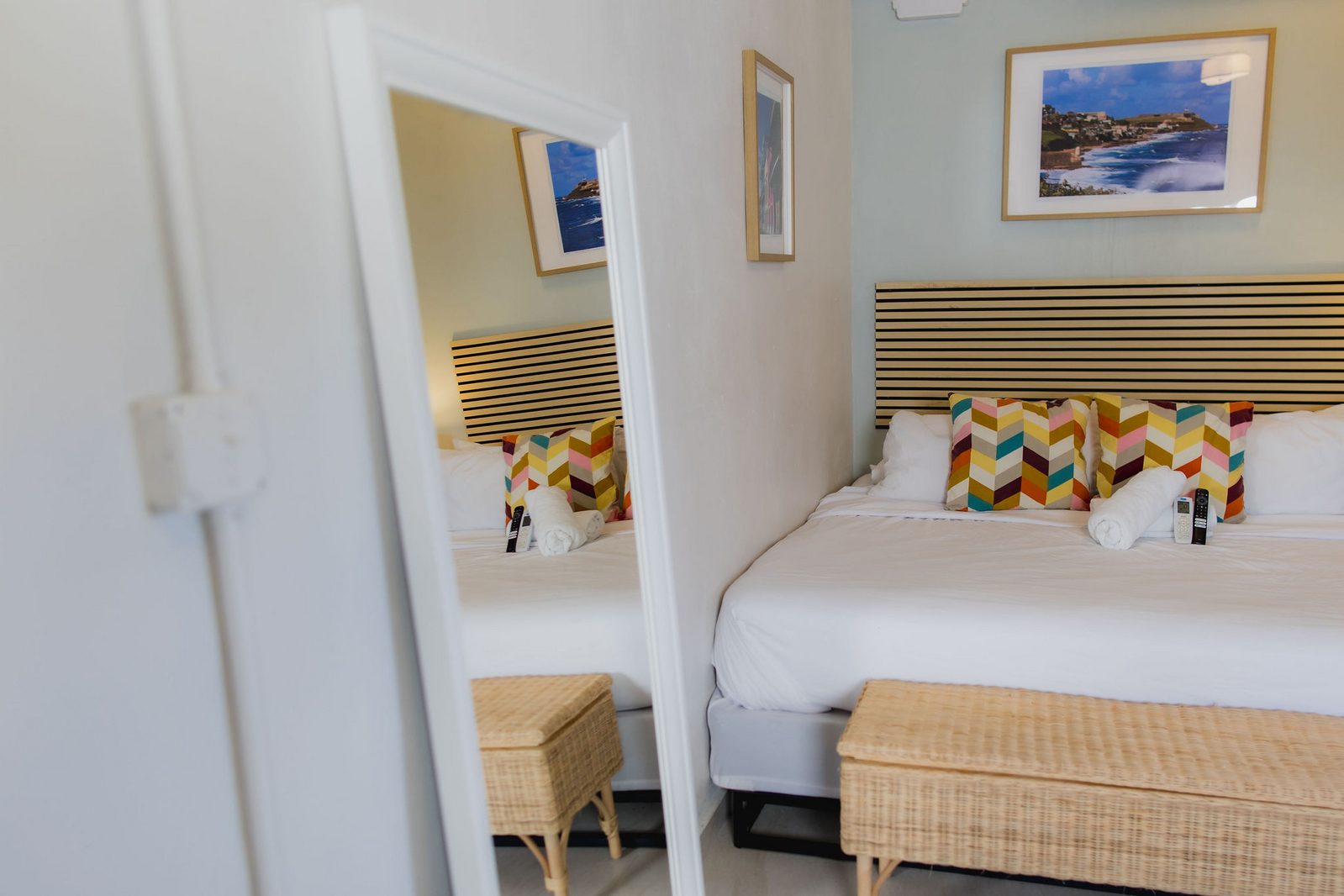 Hotel Luz guest bed with colorful chevron pillows and framed San Juan photography on the wall