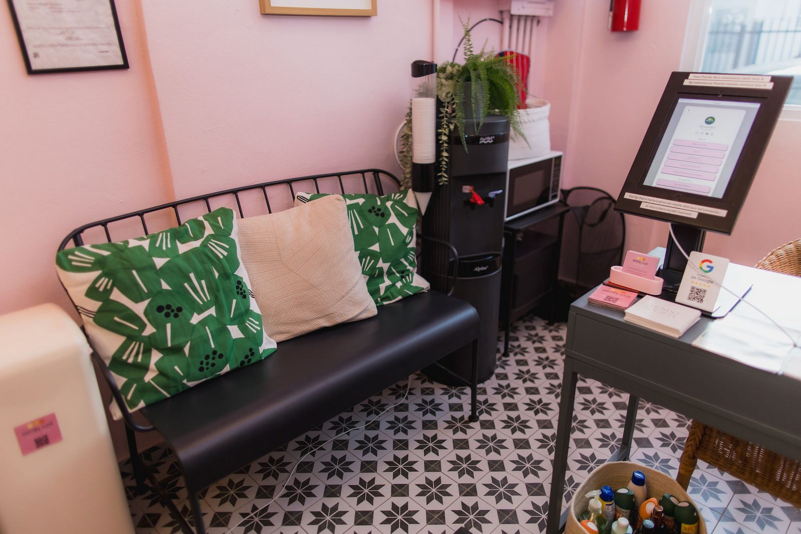 Pink-walled Hotel Luz lounge nook with a patterned bench and self check-in kiosk